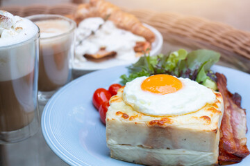 Croque Madame, French Toast with hot grilled ham and cheese with a fried egg on top. Delicious breakfast toast with thinly sliced ham, melt cheese fresh vegetable. Croque Madame with fried egg on top.