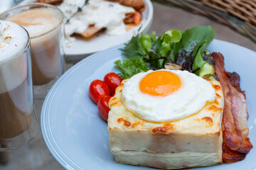 Croque Madame, French Toast with hot grilled ham and cheese with a fried egg on top. Delicious breakfast toast with thinly sliced ham, melt cheese fresh vegetable. Croque Madame with fried egg on top.