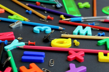 Texture, english letters and stationery for school on black background