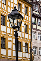 Fototapeta na wymiar An old street lamp and facades of Half-timbered wooden buildings in the German city of Nuremberg, Bavaria. Vertical detail.