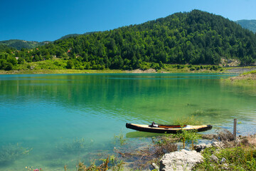 Naklejka na ściany i meble Old fishing boat on the tranquil surface of Zaovine lake in the national park Tara, Serbia
