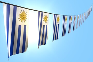 wonderful independence day flag 3d illustration. - many Uruguay flags or banners hanging diagonal on rope on blue sky background with bokeh