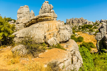 Fototapeta na wymiar Weathered limestone rock stacks and a cliff face in the Karst landscape of El Torcal near to Antequera, Spain in the summertime