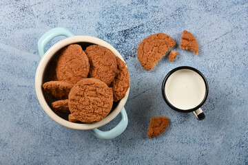 Oatmeal cookies and pannikin of milk on blue table
