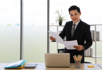 Asian business man That is positive adults Stand up and hold documents Look at the camera and smile