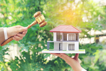 Property auction, Woman hand holding gavel wooden and model house on wtite background, lawyer of home real estate and ownership property concept