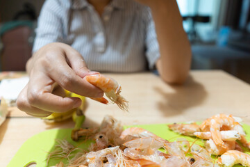 A woman peeling the steamed shrimp by hand