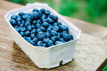 Fresh juicy blueberries in an eco bowl on a wooden table. Soft selective focus.