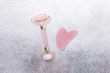 Gua Sha massager and face roller on stone background. Massage tool for facial skin care, SPA beauty treatment concept. Horizontal banner