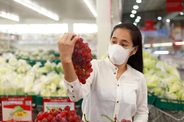 Asian woman long hair wearing protective face mask  in supermarket department store. Female,...