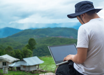 Male traveler blogger work remote on netbook computer while enjoying rice terrace nature landscape view outdoors. Young man using online banking for sending money everywhere you are from laptop