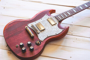 Red and white electric guitar on a white wooden table, with copy space.