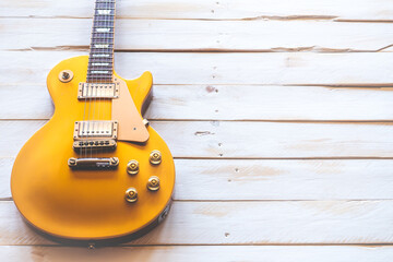 Beautiful classic golden electric guitar on a white wooden table, with copy space.