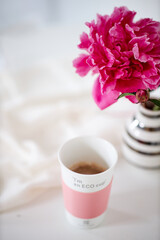 A close up of a flower and cup of coffee on a table