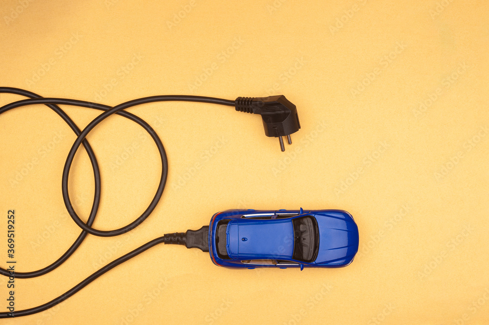 Wall mural concept of toy car charging with power cable plugged in. eco-friendly alternative energy