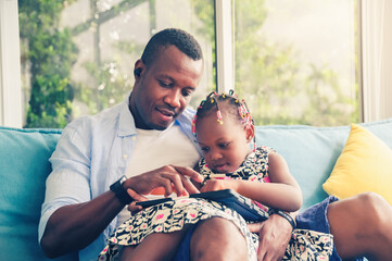 African father and daughter using looking tablet happy parents with kids relax at home in casual wear sitting on sofa in living room
