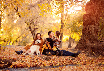 family with Retriever sitting in autumn Park.