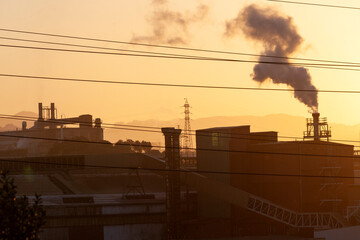 Paisaje industrial al atardecer con chimeneas echando humo