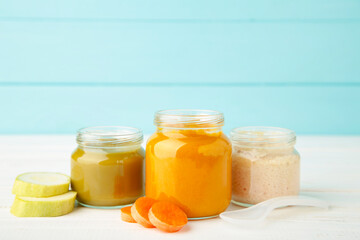 Glass jars with nutrient baby food on blue background