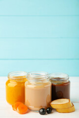 Glass jars with nutrient baby food on blue background