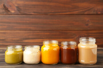Jars of baby puree on brown wooden background