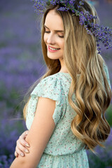 Naklejka premium Beautiful girl in lavender wreath and retro dress on the lavender field. Beautiful woman in the lavender field on sunset in France .Girl collect lavender.Soft focus. Series.