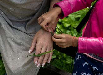 the girl ties a leaf on her grandmother's hand for good luck