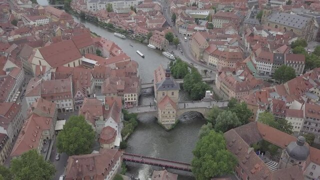 Aerial view of old town hall in Bamberg, Bavaria, Germany. House above river Main. Вridge, boats ancient historic half-timbered buildings with orange roofs. Beautiful cityscape. High quality 4k