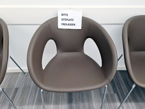 schild bitte sitzplatz freilassen an einem stuhl in einer arztpraxis wegen vorsichtsmaßnahme corona-viris