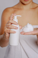 Woman pressing the liquid soap to her hand. White soap bottle with dispenser in hand.