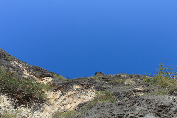 The cliffs and clear blue sky. Photographed in close range from under.