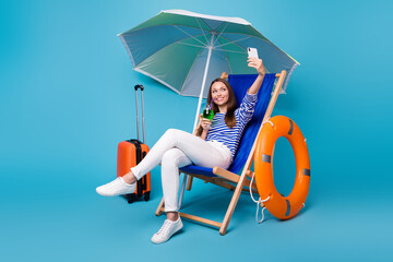 Portrait of her she nice attractive funky cheerful cheery girl sitting in chair under parasol drinking mojito taking selfie exotic leisure isolated bright vivid shine vibrant blue color background © deagreez