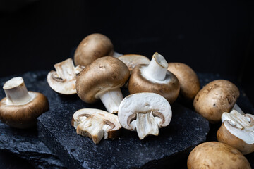 Fototapeta premium Fresh white champignons on the dark kitchen table. Cooking delicious dishes with mushrooms
