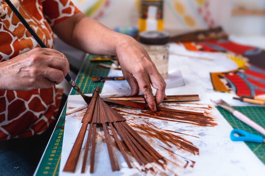 una mujer artesana pinta a mano el armazon de un abanico espa&ntilde;ol en un taller de artesania