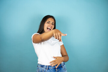 Fototapeta na wymiar Young beautiful woman over blue background laughing at you, pointing finger to the camera with hand over body, shame expression