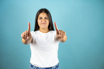 Young woman over blue isolated background saying no with fingers, angry and frustration expression