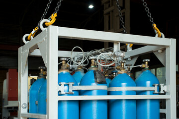 Oxygen cylinders in a cassette suspended from the hooks of a crane in the workshop of the plant.