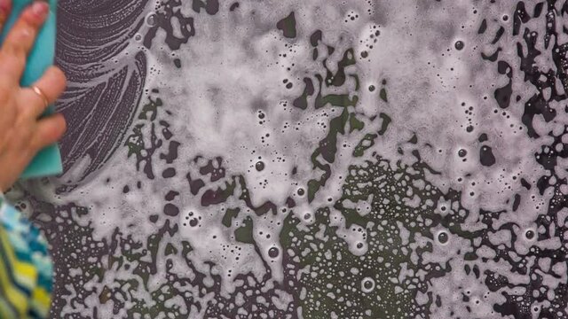 Female hand lathers the window