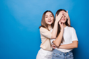 Naklejka premium two women one hide eyes do not look guess who wear casual t-shirts isolated blue background
