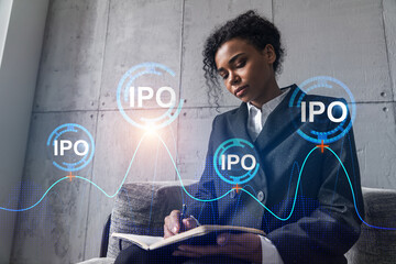 Businesswoman taking notes and IPO hologram. Double exposure. Business technology initial primary...