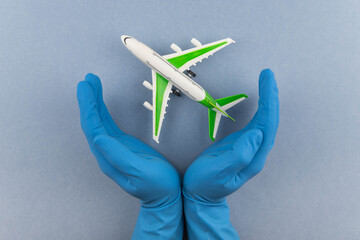 Safe travels concept. Plane in hands in medical gloves. Safety flight and travel during quarantine and lockdown.