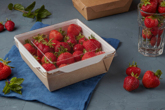 Strawberries in eco carton packaging, vegetarian food, gray background