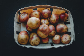 Canary islands potatoes, pink variety in a basket over dark backround (Canarian pink potatoes)