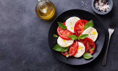 Caprese salad with tomatoes, mozzarella cheese, basil. Dark background. Copy space. Top view.