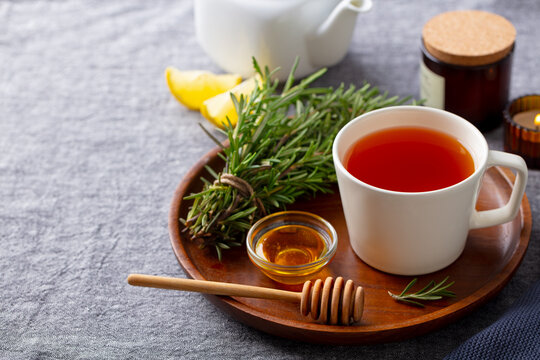 Tea cup with rosemary, honey and lemon. Grey background. Close up. Copy space.