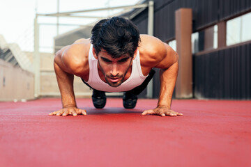 handsome sportsman doing push ups on a red floor