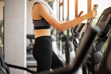 Fototapeta premium Young woman doing exercise cardio on elliptical trainer at gym.