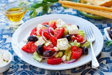 Greek salad. Fresh vegetables, feta cheese and black olives. Blue background. Close up.
