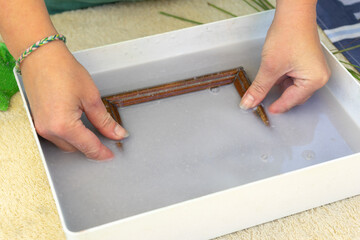 Woman holding frame for making paper sheets from waste paper pulp. Selective focus. Decorative and applied art. Recycling concept, ecology.