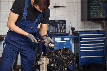 Professional repairman in black protective mask works with broken automobile engine